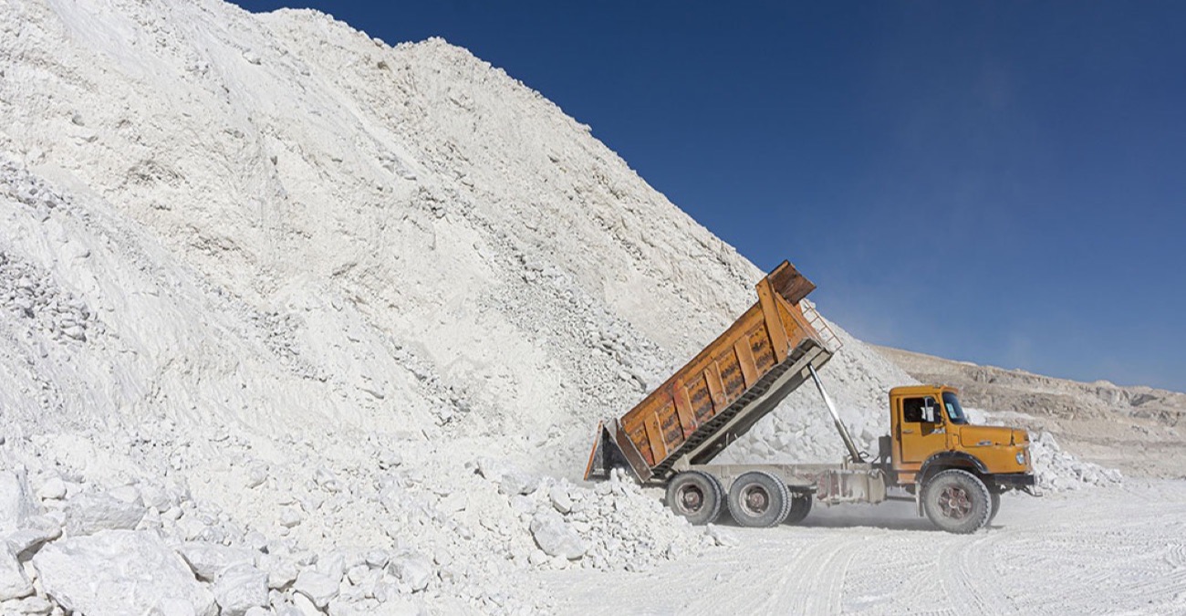Dump truck unloading beside a white gypsum stockpile