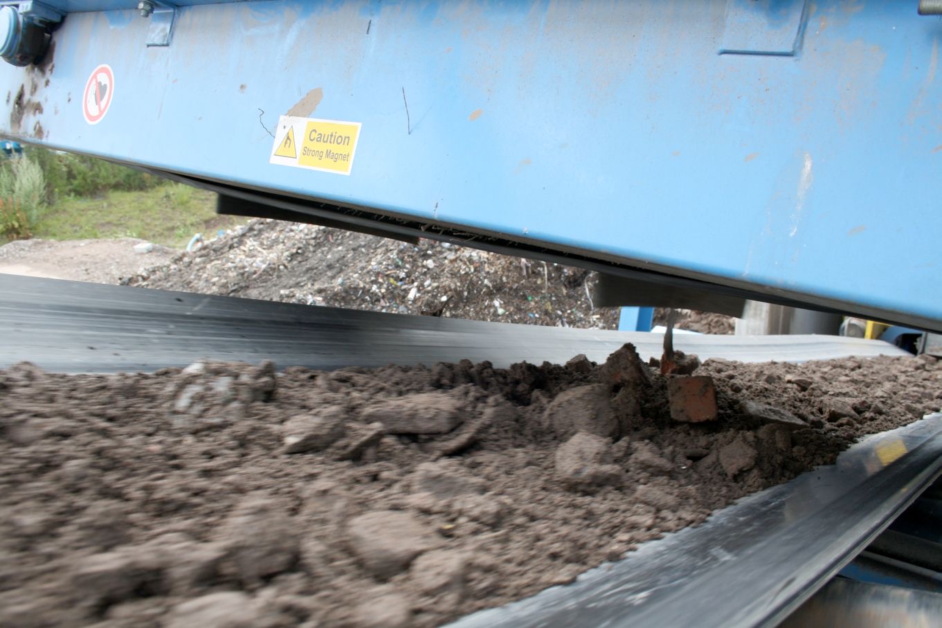 Overband magnet suspended above a feed conveyor