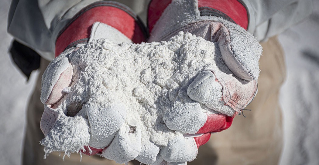 Gloved hands holding freshly quarried white mineral